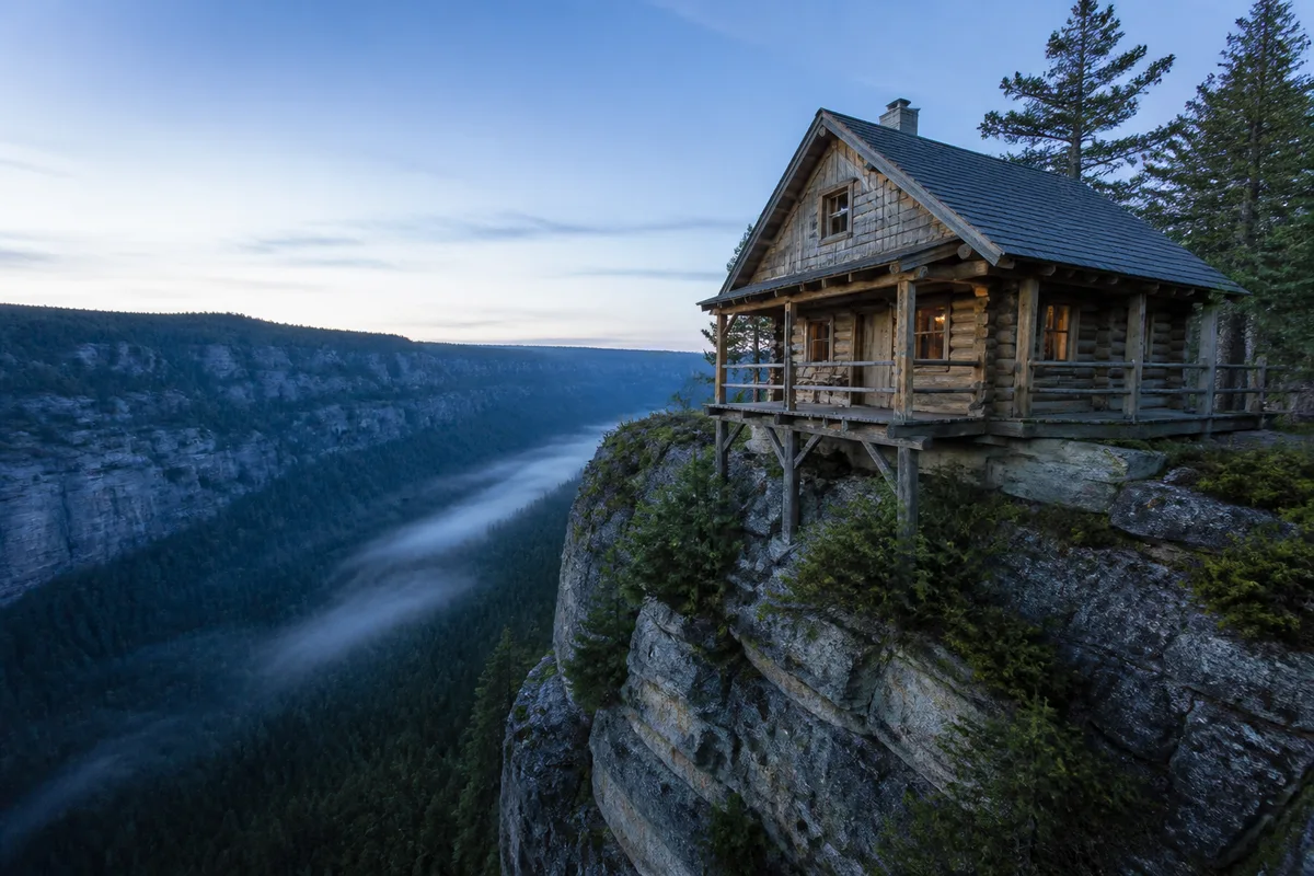 Petit chalet de bois au bord d&rsquo;une falaise dominant un canyon boisé