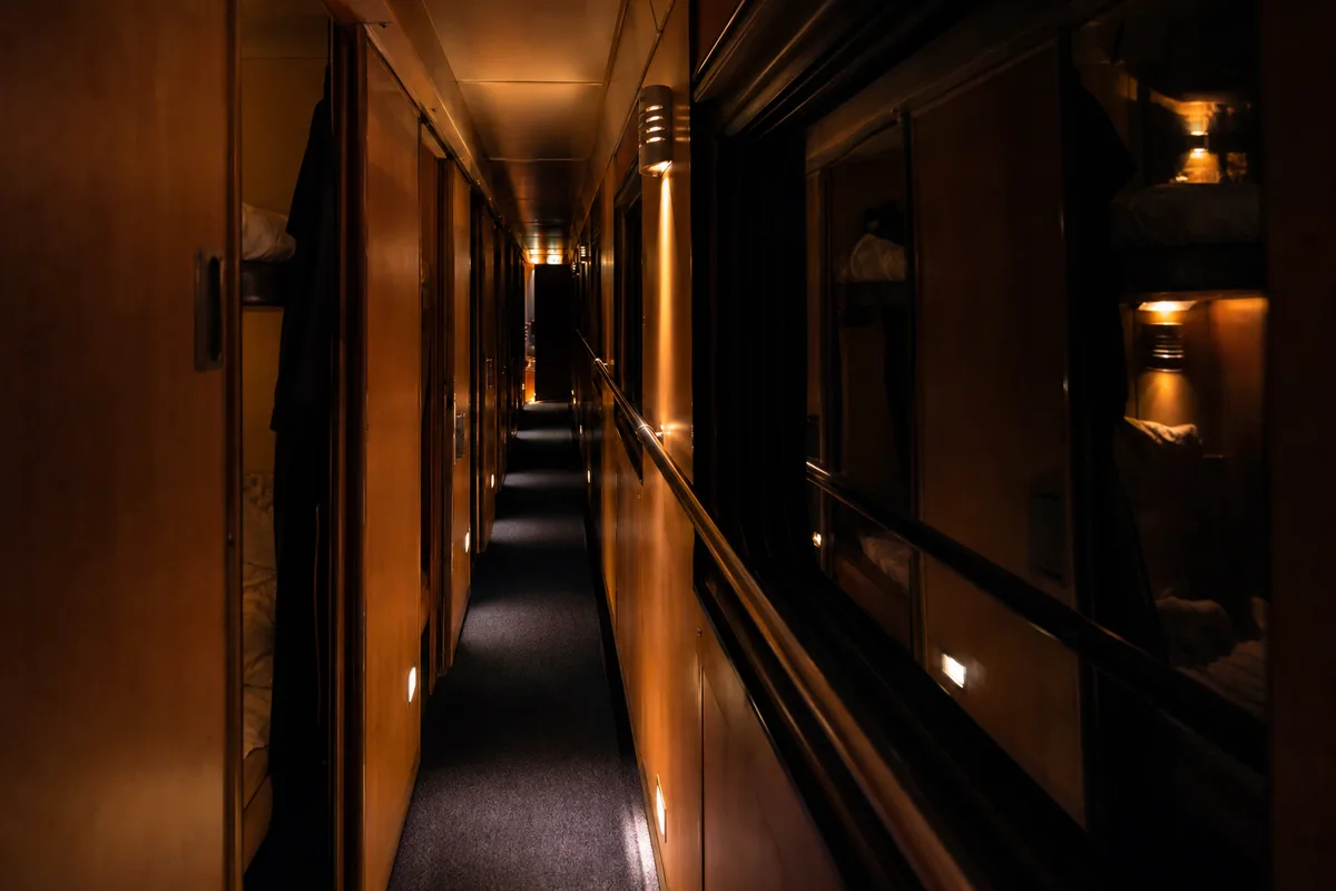 Couloir étroit d&rsquo;une voiture-couchettes éclairé de veilleuses pendant la nuit